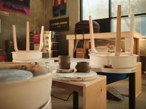 Workbenches in the Create Makerspace studio, potters wheels and tools with finished pieces drying